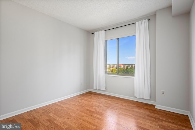 empty room with a textured ceiling and light wood-type flooring