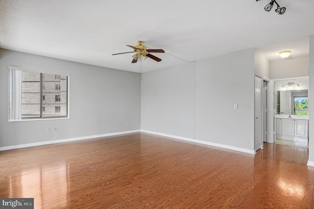 spare room featuring hardwood / wood-style flooring, ceiling fan, and a textured ceiling