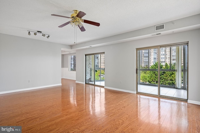 unfurnished room featuring ceiling fan, light hardwood / wood-style flooring, and a textured ceiling