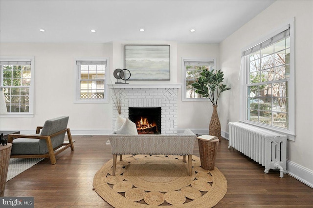 interior space featuring dark wood-type flooring, radiator heating unit, and a brick fireplace