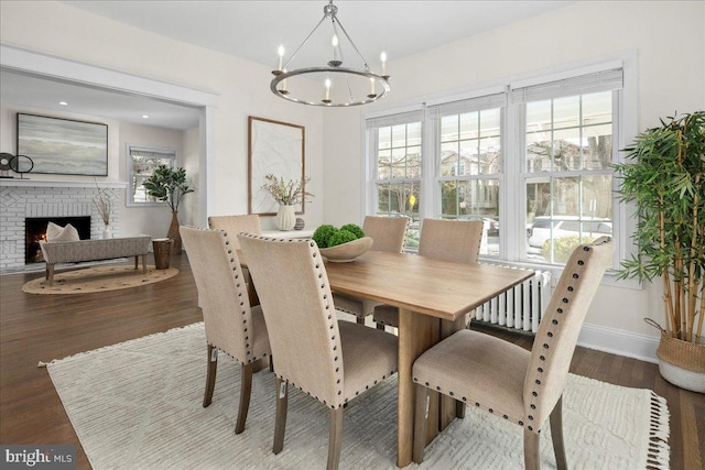 dining room featuring an inviting chandelier, a fireplace, and wood-type flooring