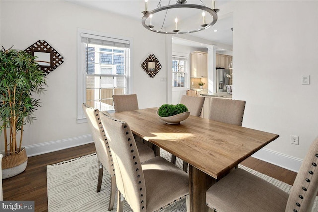 dining area featuring an inviting chandelier, dark wood-type flooring, and decorative columns