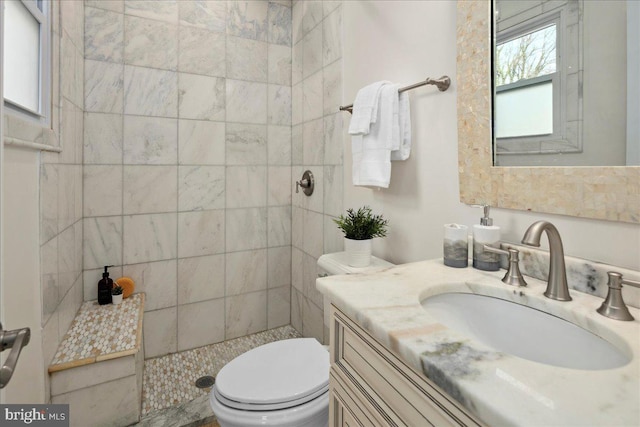 bathroom featuring tiled shower, vanity, and toilet