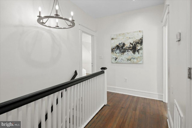 hall with dark wood-type flooring and a chandelier