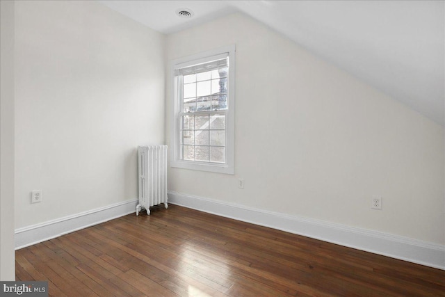 additional living space featuring vaulted ceiling, dark hardwood / wood-style floors, and radiator heating unit