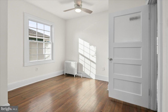 empty room featuring radiator heating unit, dark hardwood / wood-style floors, and ceiling fan