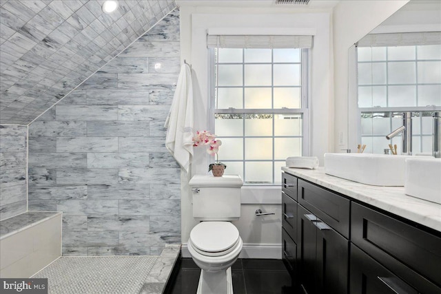 bathroom featuring vanity, a tile shower, and toilet