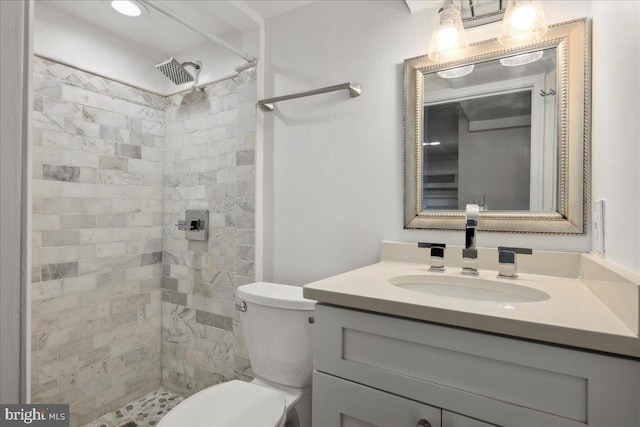 bathroom featuring vanity, toilet, and a tile shower