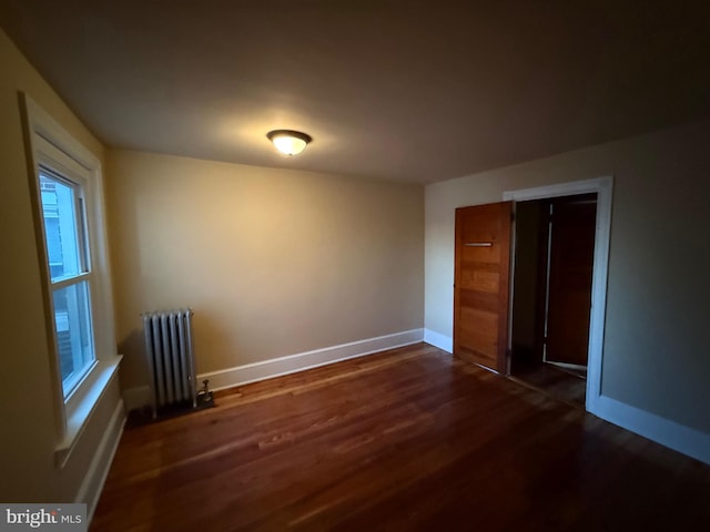 unfurnished room featuring dark hardwood / wood-style floors and radiator