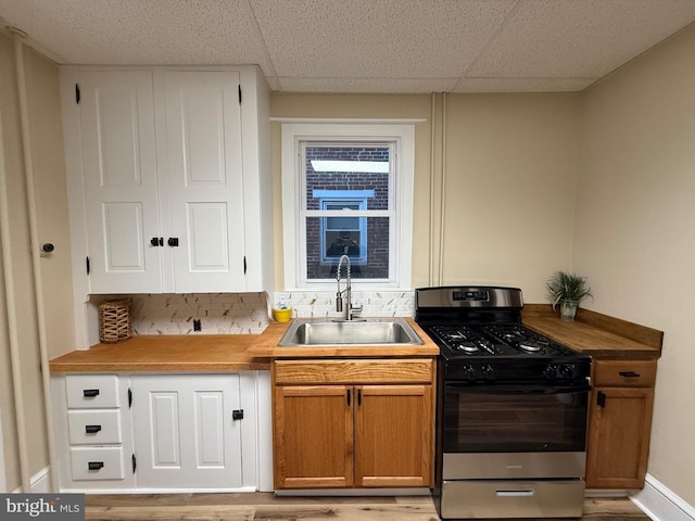 kitchen featuring gas range, sink, light hardwood / wood-style flooring, and a drop ceiling