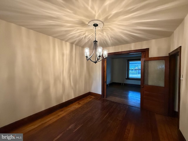 unfurnished dining area featuring dark wood-type flooring and a chandelier