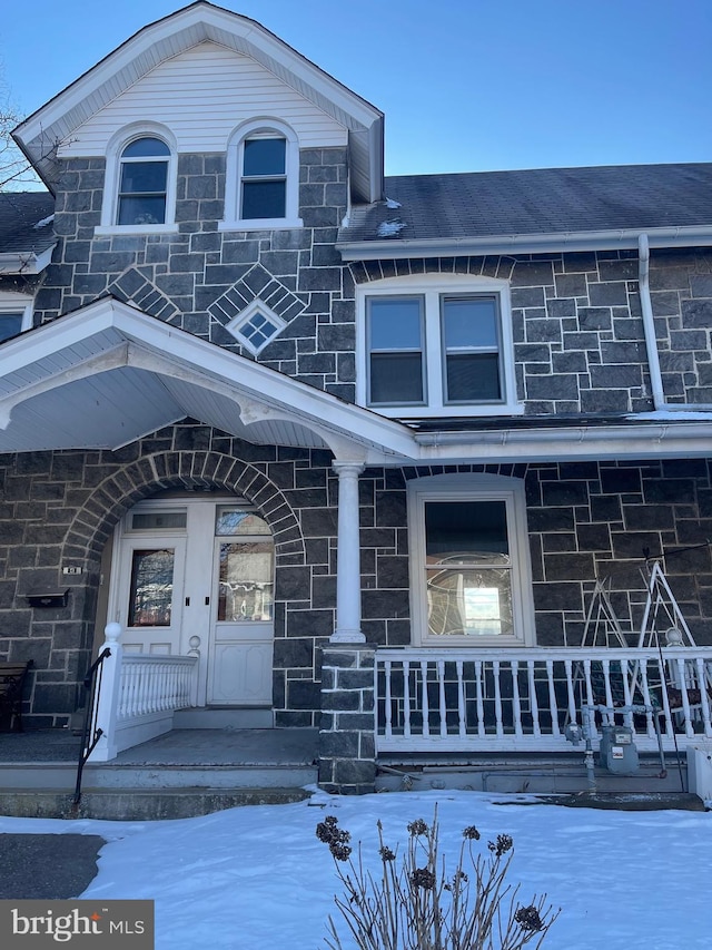 snow covered property entrance with covered porch