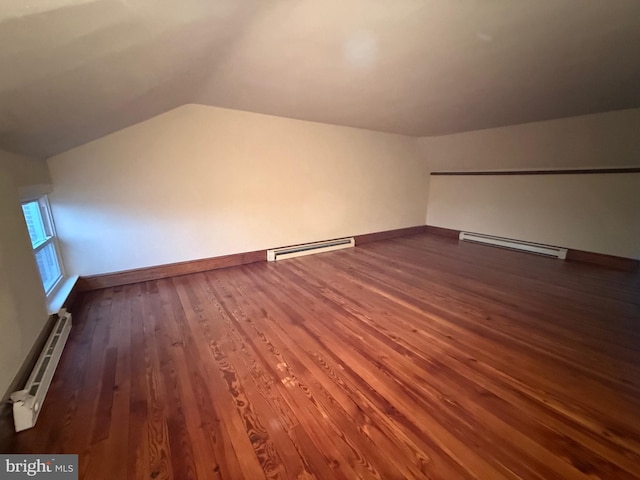 additional living space featuring lofted ceiling, a baseboard heating unit, and dark hardwood / wood-style floors