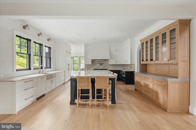 kitchen featuring a kitchen island, white cabinets, a kitchen breakfast bar, decorative backsplash, and light hardwood / wood-style flooring