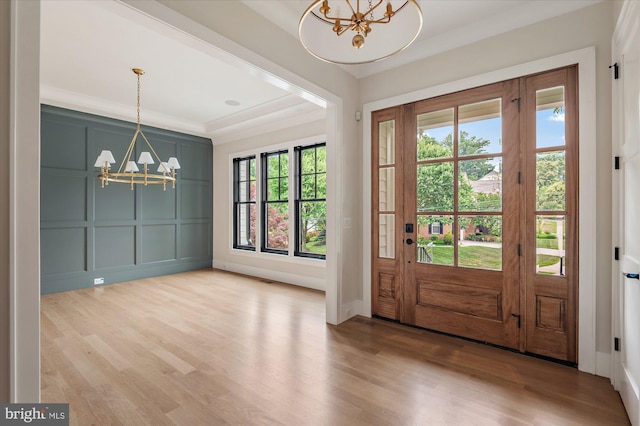 interior space with a chandelier, plenty of natural light, wood finished floors, and a decorative wall