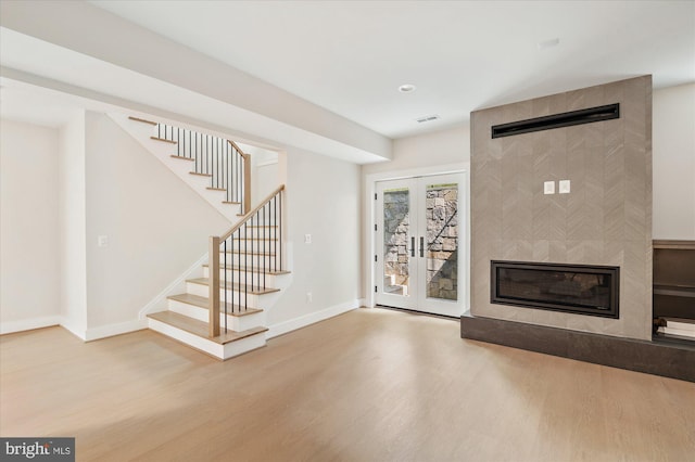 unfurnished living room featuring french doors, a fireplace, and hardwood / wood-style floors