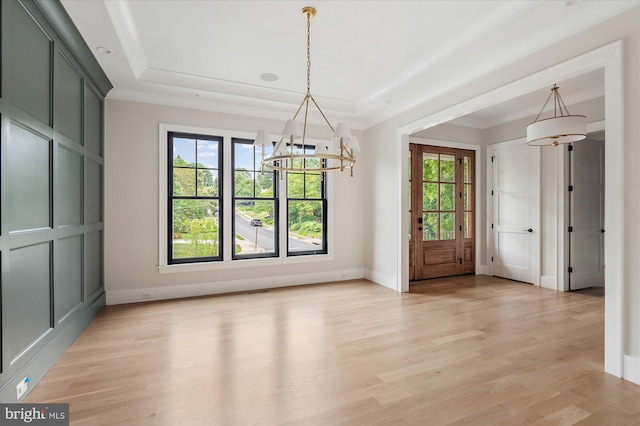 unfurnished dining area with a tray ceiling, light hardwood / wood-style flooring, and ornamental molding