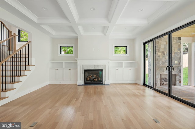 unfurnished living room featuring a fireplace, coffered ceiling, baseboards, light wood finished floors, and beamed ceiling