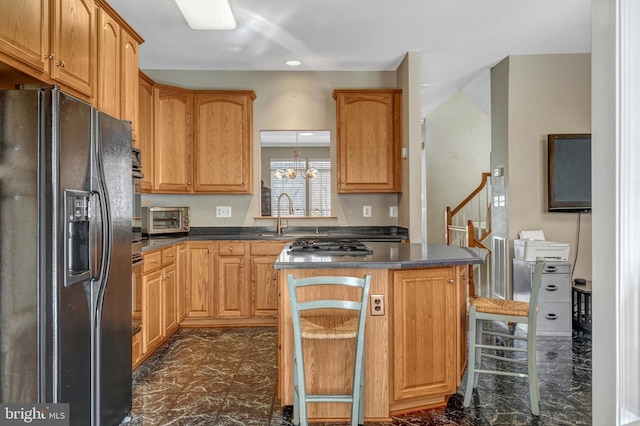 kitchen featuring sink, a kitchen bar, a center island, an inviting chandelier, and black refrigerator with ice dispenser