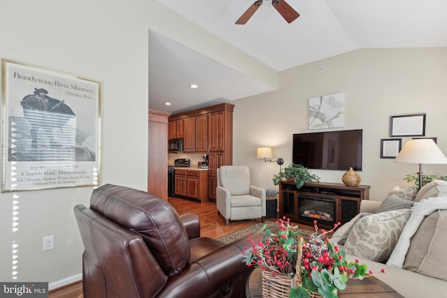 living room featuring ceiling fan, wood-type flooring, and vaulted ceiling