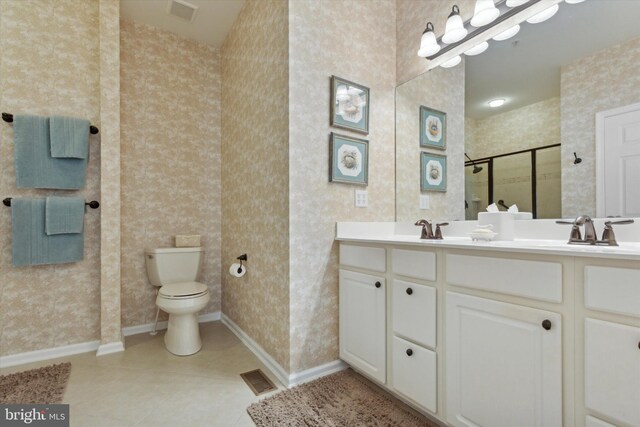 bathroom with vanity, tile patterned floors, toilet, and a shower