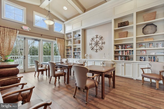 dining room featuring beam ceiling, high vaulted ceiling, light wood-type flooring, and built in shelves