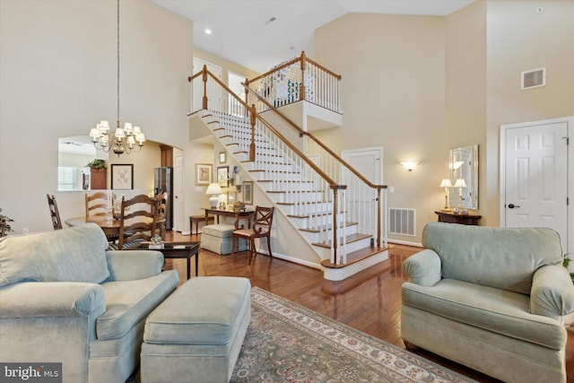 living room with hardwood / wood-style flooring, high vaulted ceiling, and a chandelier