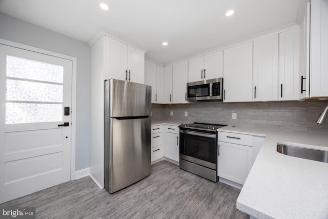 kitchen with appliances with stainless steel finishes, sink, white cabinets, and backsplash