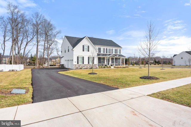 view of front of property featuring a garage, a front lawn, and covered porch