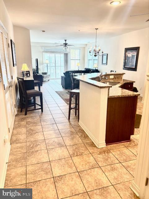 kitchen featuring pendant lighting, sink, ceiling fan with notable chandelier, and light tile patterned floors