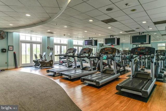 exercise room featuring wood-type flooring, a paneled ceiling, and french doors