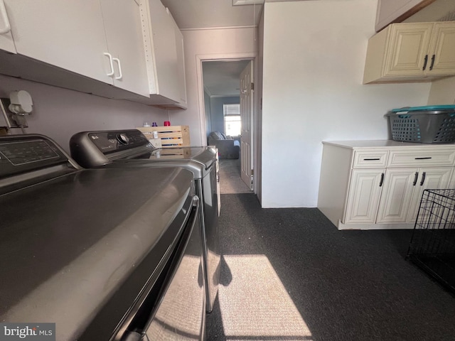 clothes washing area featuring dark carpet, washer and clothes dryer, and cabinets