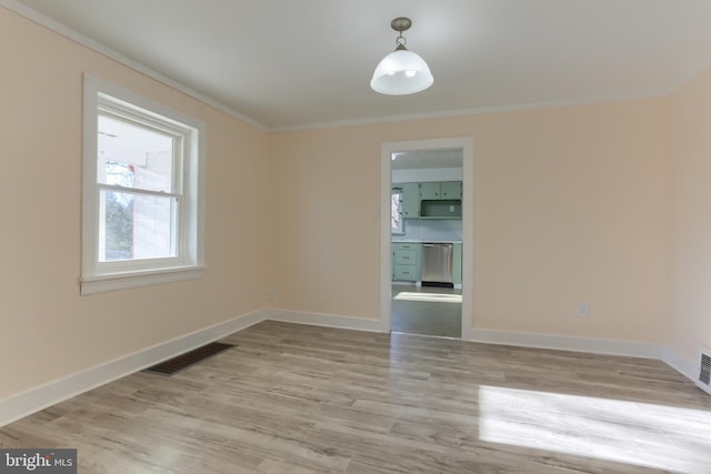 unfurnished room featuring ornamental molding and light wood-type flooring