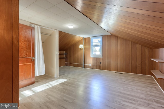 bonus room with vaulted ceiling, light hardwood / wood-style floors, and wood walls