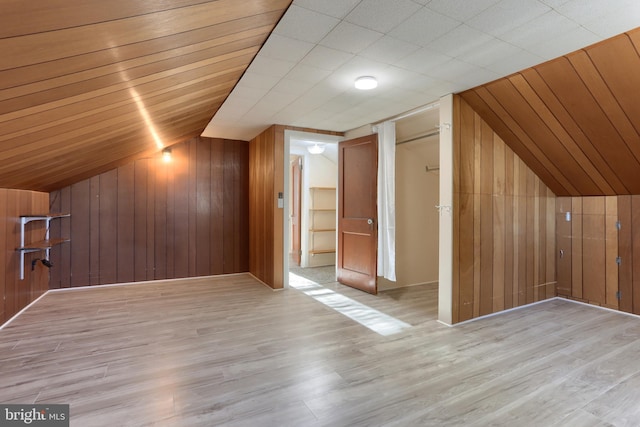 additional living space with vaulted ceiling, light wood-type flooring, wood ceiling, and wooden walls