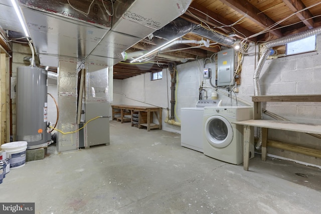 basement with washing machine and clothes dryer, electric panel, heating unit, and gas water heater