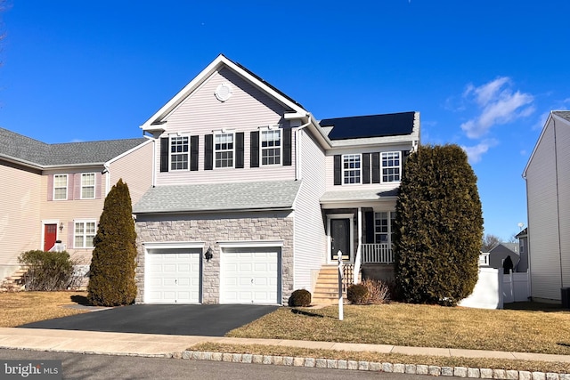 view of property featuring a garage, a front lawn, and solar panels