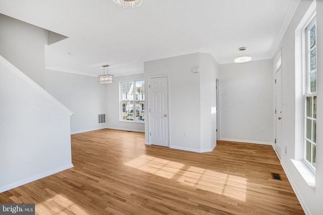 unfurnished living room with hardwood / wood-style flooring, crown molding, and a notable chandelier