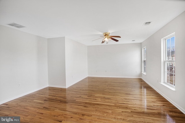 empty room featuring ceiling fan, hardwood / wood-style floors, and a wealth of natural light