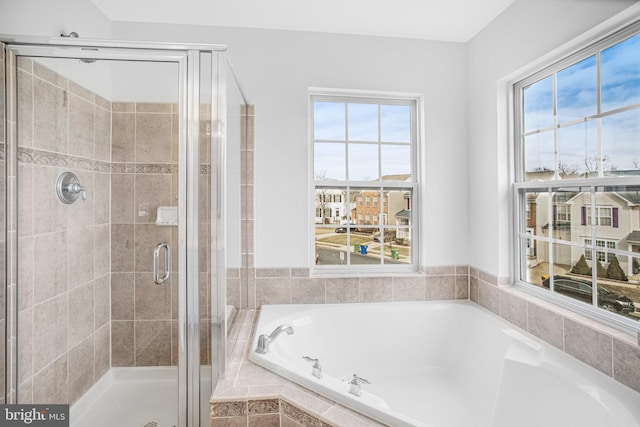 bathroom featuring a healthy amount of sunlight and separate shower and tub