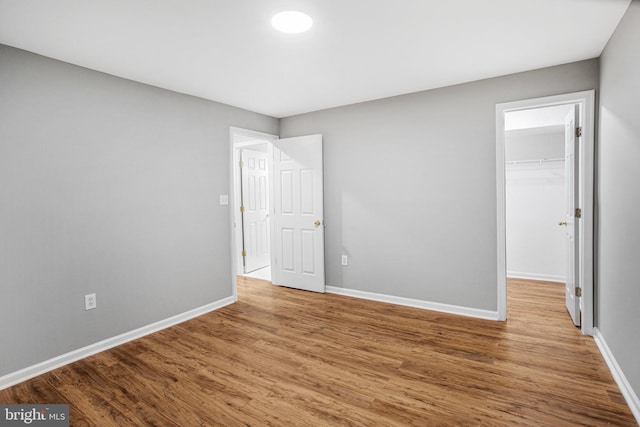 unfurnished bedroom with a spacious closet, hardwood / wood-style floors, and a closet