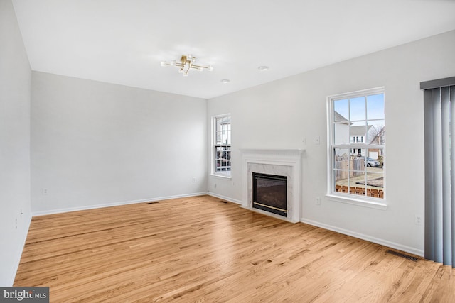 unfurnished living room with a high end fireplace and light hardwood / wood-style floors