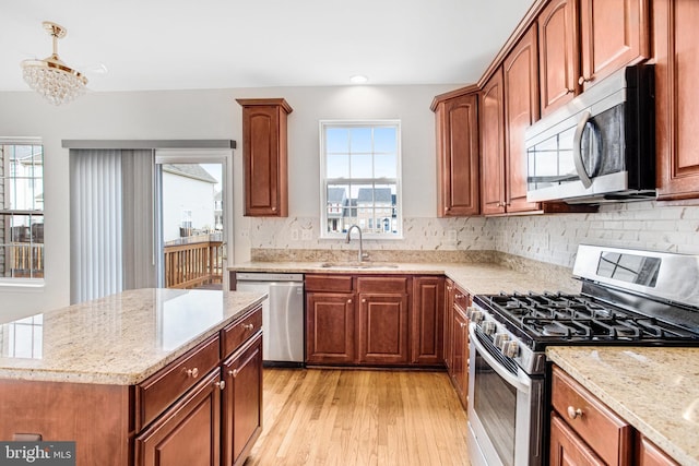 kitchen featuring sink, tasteful backsplash, light hardwood / wood-style flooring, appliances with stainless steel finishes, and light stone countertops