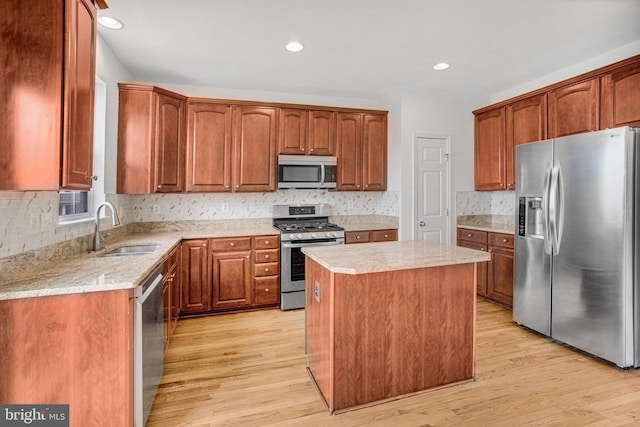 kitchen with a center island, appliances with stainless steel finishes, sink, and light wood-type flooring