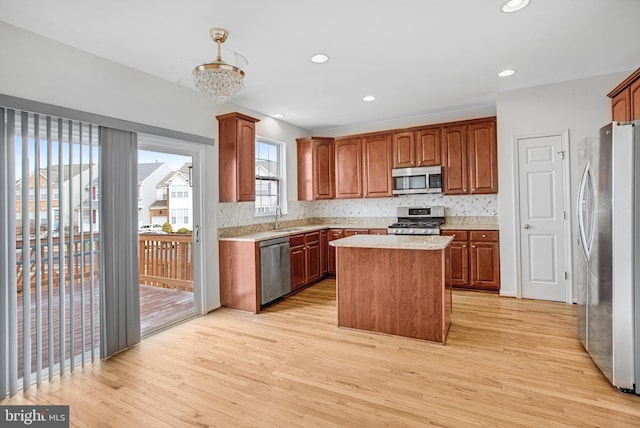 kitchen featuring sink, light hardwood / wood-style flooring, appliances with stainless steel finishes, backsplash, and a center island