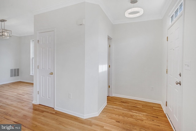 corridor featuring ornamental molding, a chandelier, and light wood-type flooring