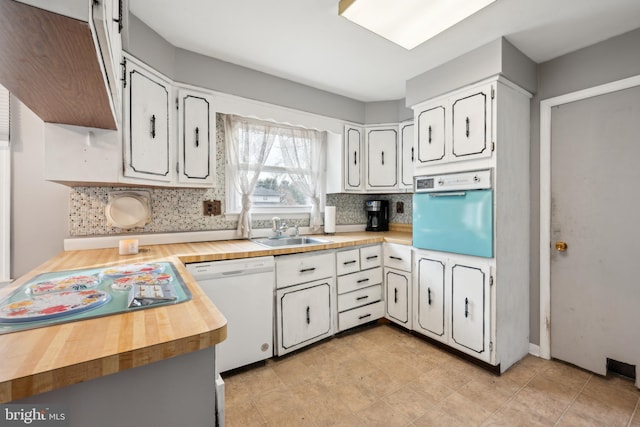 kitchen featuring sink, white dishwasher, white cabinets, decorative backsplash, and oven