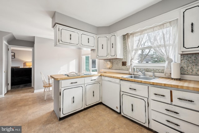 kitchen with sink, white dishwasher, kitchen peninsula, decorative backsplash, and white cabinets