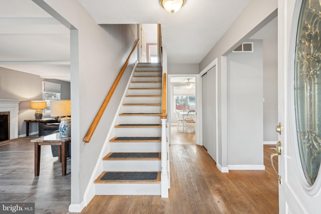 stairs featuring a tiled fireplace and hardwood / wood-style floors