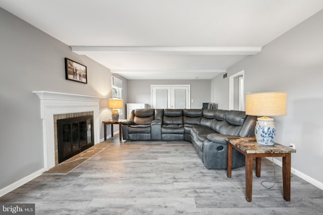 living room featuring a fireplace, beam ceiling, and light hardwood / wood-style floors